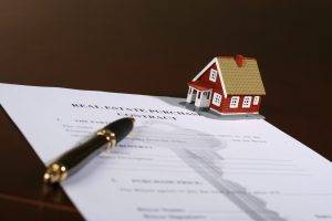 probate homes for sale, Purchase contract on a table with a pen and tiny model of a 2-story red color home with white trim probate homes for sale, Purchase probate homes for sale