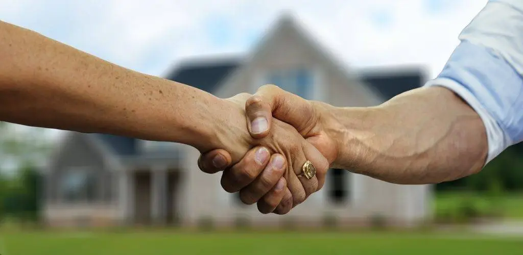 Executor Selling House, Probate agent shaking hands with an executor with a house in the background Executor Selling House, with Probate Real Estate Agent