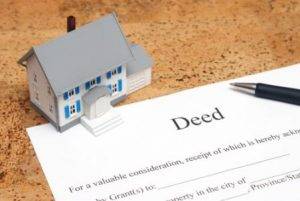 Beneficiaries, Deed with a pen and image of a home siting on a desktop Beneficiaries, Title transfer deed