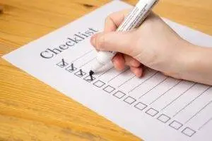 Trusts, Checklist on a desktop with a hand holding a pen checking boxes on the list Trusts, Trust Administration Checklist