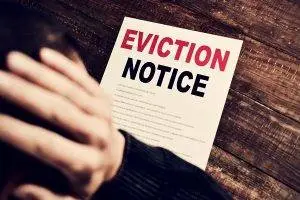 laws for quicker evictions, Young man holding his head looking at an eviction notice Eviction Notice - California laws for quicker evictions